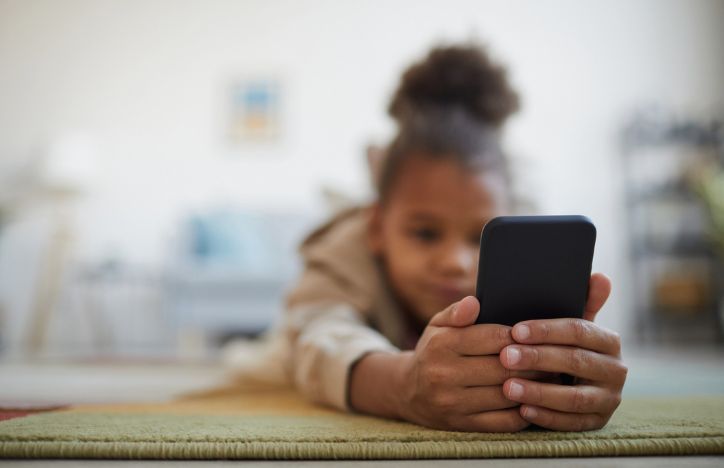 Child Lying On Floor And Using Smartphone