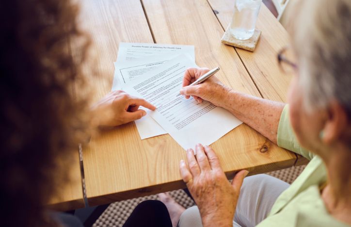 Older Woman Signing A Piece Of Paper